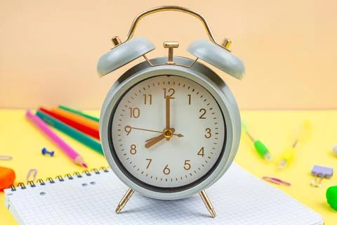 A Classic Alarm Clock Positioned Next to Various Stationery Supplies for a .. Stock Photos