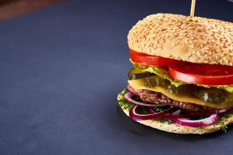 Classic American cheeseburger with black flag on the top over dark background Stock Photos