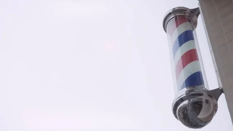 A classic barber pole set against a clouded sky background that is perfect as Stock Footage 75405018