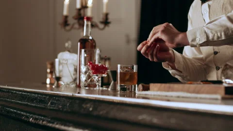 Classic bartender garnishing cocktail with an orange peel and cherry and serving Video stock 199455232
