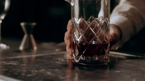 Classic bartender placing cubes of ice into a glass and begins to stir with a lo Stock Footage 199455303