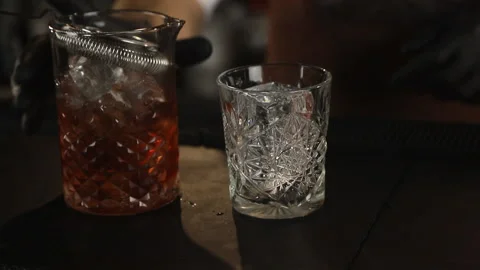 Classic bartender pouring liquor from a tall glass to a cocktail glass Stock Footage 124406181
