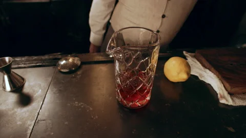 Classic bartender putting cubes of ice into a tall glass in interior classy bar Stock Footage 199463443