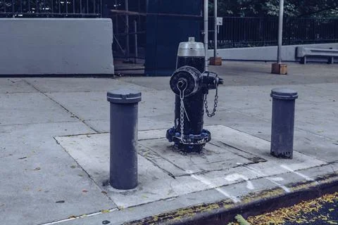 Classic Black US-style fire hydrant seen installed on a New York sidewalk. Stock Photos