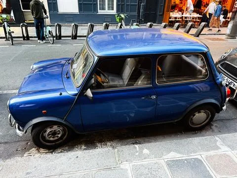Classic blue compact Mini car parked on a Paris, France street outside a ca.. Foto stock