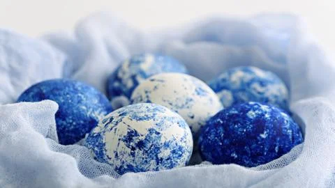Classic blue eggs with gradient effect in textile nest for Easter on white ba Stock Photos