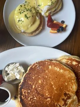Classic Brunch Spread with Eggs Benedict, Pancakes, and Fresh Fruit Sides Stock Photos