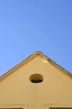 Classic building triangular gable with an oval window under a blue sky Stock Photos