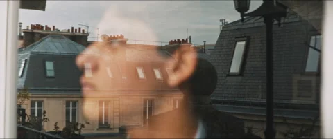 Classic buildings reflection on a window while a young man stares outside Stock Footage 203586112