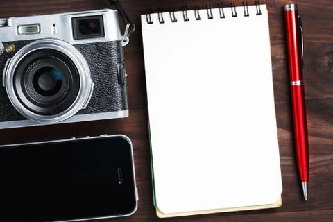 Classic camera with blank notepad page and red pen on dark brown wooden table 写真素材
