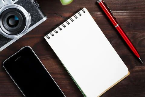 Classic camera with blank notepad page and red pen on dark brown wooden table Foto stock
