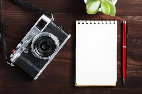 Classic camera with blank notepad page and red pen on dark brown wooden table Foto stock