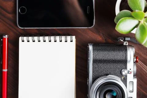 Classic camera with blank notepad page and red pen on dark brown wooden table Stock Photos