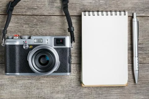 Classic camera with blank notepad page and gray pen on gray wooden, vintage d Stock Photos