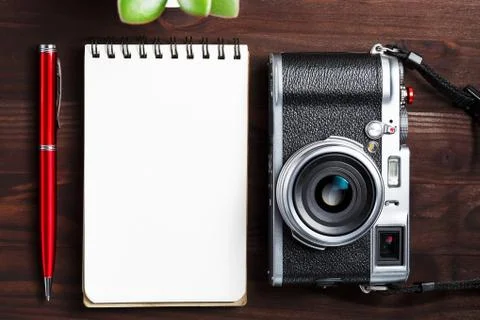 Classic camera with blank notepad page and red pen on dark brown wooden table 写真素材