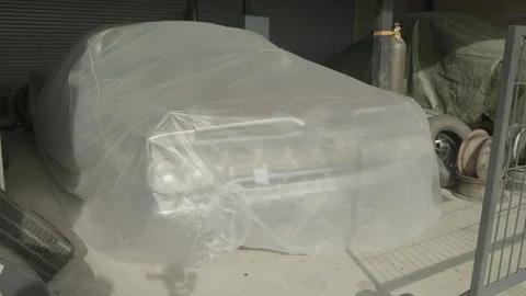 Classic car covered in protective plastic sheet Vídeo Stock 335732359