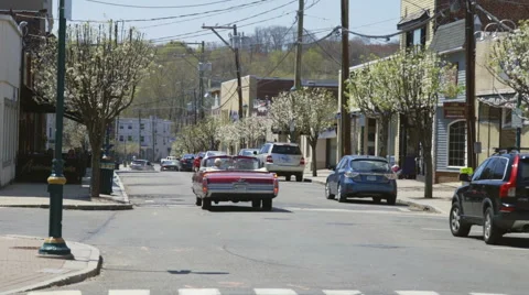 Classic car cruises down small town street Stock Footage 50294921