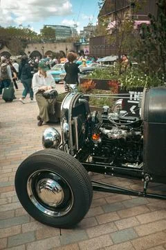 Classic car engine and wheel with event crowd in background Stock Photos