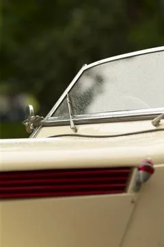 Classic car windshield with raindrops, chrome wiper arm and cream paint detail Stock Photos