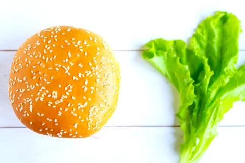Classic cheeseburger and fresh salad leafs on wooden background. Top view. Stock Photos