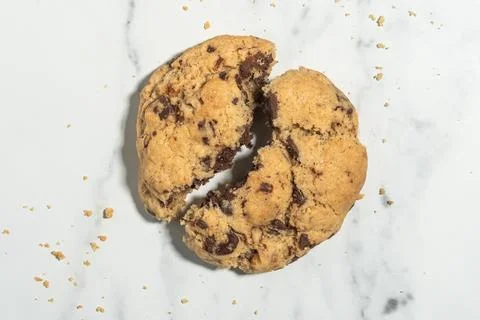 Classic chocolate chip cookie split in two ready to eat on a minimalist whi.. 库存照片