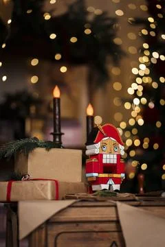 Classic Christmas Nutcracker in red uniform stands next to gifts wrapped in c Stock Photos