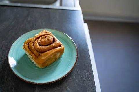 Classic cinnamon roll on an artisan plate in the kitchen top view Stock Photos
