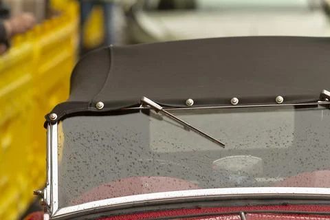 Classic convertible windshield with raindrops and folded black soft top closeup Stock Photos