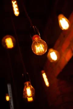 Classic different retro light bulbs hanging on brick wall background at night Foto stock