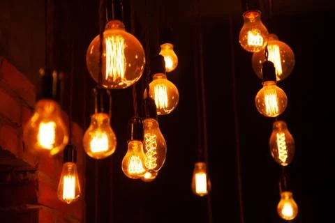Classic different retro light bulbs hanging on brick wall background at night Stock Photos