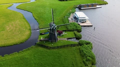 A classic Dutch windmill stands in the middle of lush green fields, beside 스톡 동영상 313276159