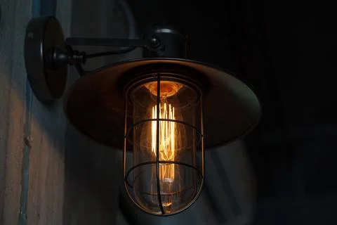 A classic Edison light bulb on old wall background switched on. Stock Photos