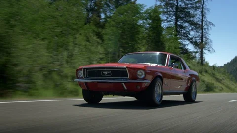 Classic Ford Mustang in 3 quarter, accelerates past camera. Stock Footage