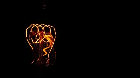 Classic glowing eddison lamp close-up on black background. an old incandescen Stock Footage 105460007