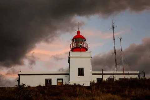 The classic lighthouse with red head during the sunset, dramatic clouds in th Stock Photos
