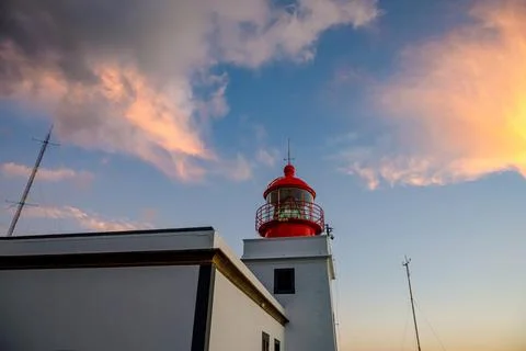 The classic lighthouse with red head during the sunset, dramatic clouds in th Stock Photos