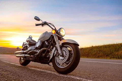Classic motorcycle chopper, cruiser on empty asphalt road on sunset sky Stock Photos