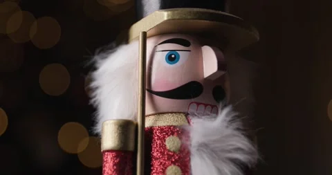 Classic Nutcracker figurine elegantly spinning in front of glowing bokeh lights, Stock Footage 287176922