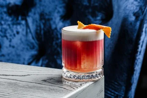 Classic old fashioned red Cocktail in a retro glass with ice and orange peel  Stock Photos
