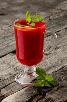 Classic raspberry tea with mint in a glass on a rustic wooden background. Space Stock Photos