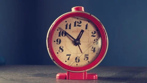 Classic red alarm clock displaying time in a stylish setup against a blue 動画素材 297598304
