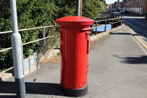 A classic red British post box, standing as a focal point. Stock Photos
