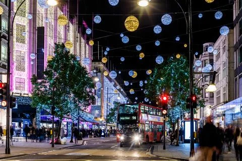 Classic red double-decker bus on festive London street at night Stock Photos