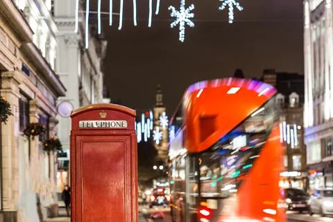 Classic red double-decker bus on festive London street at night Stock-Fotos