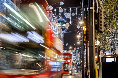 Classic red double-decker bus on festive London street at night Stock Photos