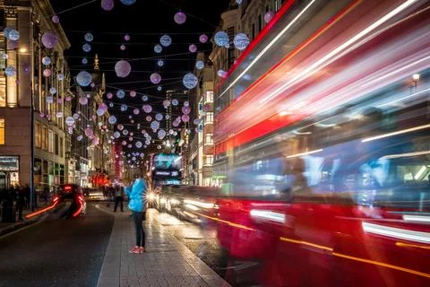 Classic red double-decker bus on festive London street at night Stock Photos