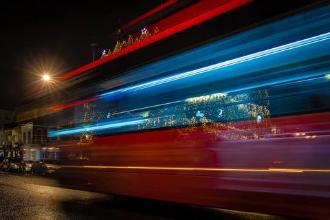 Classic red double-decker bus on festive London street at night Stock Photos
