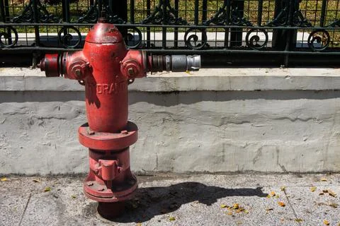 Classic red fire hydrant standing on paved walkway under bright outdoor sun.. Stock Photos
