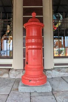 A classic red post office box stands proudly on a sandstone paved street Stock Photos