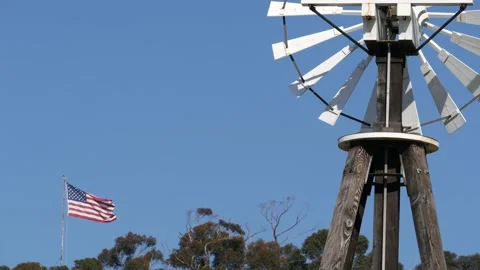 Classic retro windmill, bladed rotor and USA flag against blue sky. Vintage Stock Footage 137958371